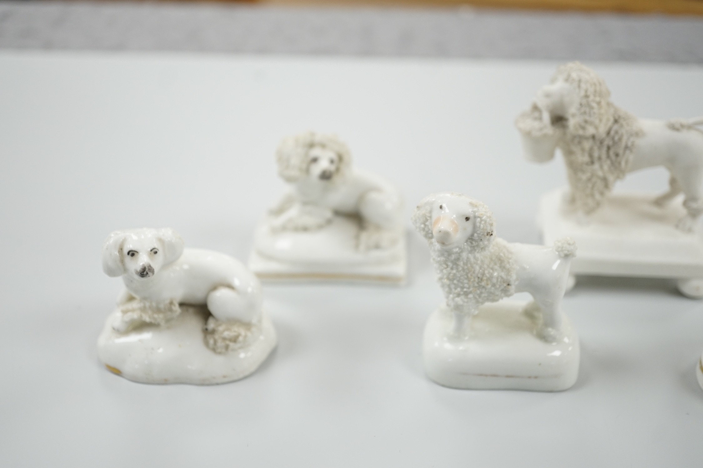 Five small Staffordshire models of poodles, together with a small poodle lying recumbent on an oval mounted base, possibly Davenport, c.1830-50, (6). Tallest 6.8cm., Provence: Dennis G. Rice collection, Cf. Dennis G.Rice